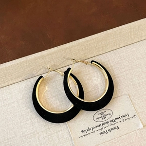 Detail of vintage C-shaped hoop earrings with black flocking and gold metal finish