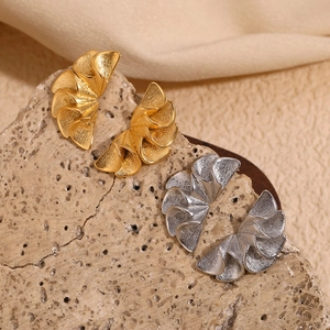Macro shot of gold and silver pleated petal earrings on natural stone surface
