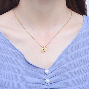 Golden snail pendant necklace and earring set shown on model with light blue top