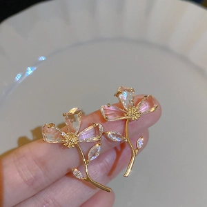 Macro view of gold flower earrings with clear zircon crystals and petal details