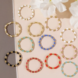 Set of 12 colorful handmade seed bead rings with gold accents in various bright colors