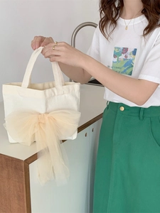 Canvas Tragetasche mit großer Champagner-Netzschleife getragen von Modell im Sommeroutfit