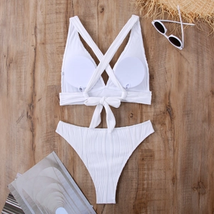 Detailansicht eines weißen Ripp-Bikinis mit Rückenschleife und Sommeraccessoires