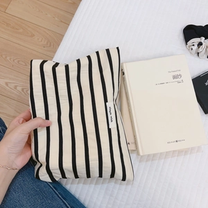 Minimalist black and white striped cotton canvas cosmetic bag on a cozy fabric background