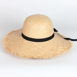 Détail de la texture d'un chapeau de soleil en raphia avec bords effilochés et ruban noir