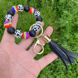 Close-up of silicone beaded keychain bracelet with cow print and tassel on grass