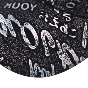 Macro shot of thick fabric with silver glitter graffiti font on a black baseball cap