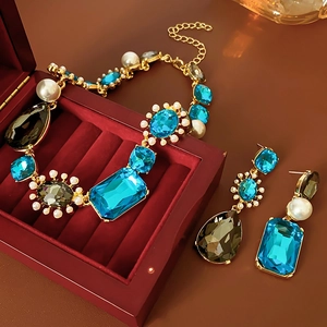 Detail of luxury teardrop crystal necklace and pearl earrings in a red velvet jewelry box
