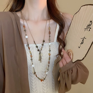 Dettaglio di una collana bohémien vintage a strati con nappe metalliche e perline