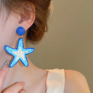 Detail von übergroßen Bast-Ohrringen in Seesternform im blau-weißen Boho-Stil