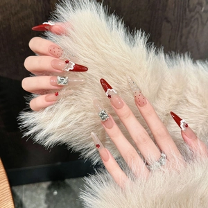 Festive red and nude press-on nails with 3D rhinestones and star charms on stiletto tips