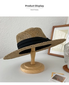 Detail of hand-woven seagrass sun hat with black ribbon on a wooden stand
