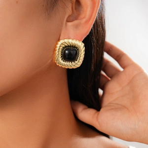 Detailed close-up of a vintage square gold earring with a black gemstone on model