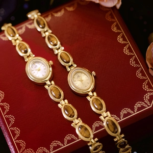 Detail of vintage gold watches with oval dials and tiger eye stone inlay on a red box