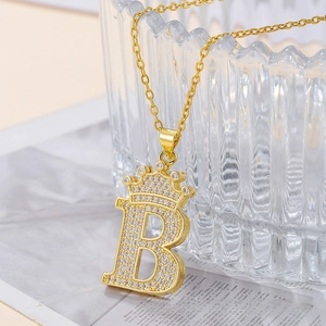 Detailed close-up of crown letter B pendant with white zircon inlays on golden chain