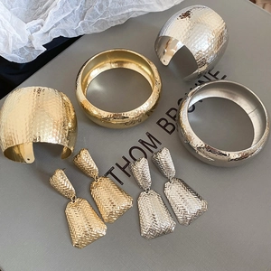 Macro shot of gold and silver metallic textured bangle bracelets and geometric earrings set