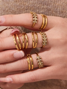 Close-up of 18k gold plated leaf rings and zircon sets on a textured knit background