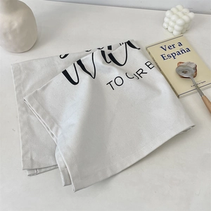 Close-up of a minimalist cream canvas placemat with black artistic typography and texture