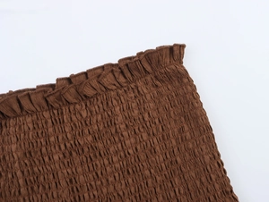Close-up of brown smocking fabric with delicate ruffle edge and elastic texture