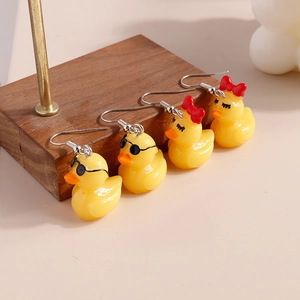 Detailed view of yellow duck earrings with sunglasses and red bow tie accents