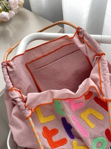 Close-up of pink canvas tote bag showing colorful chenille patches and inner pocket