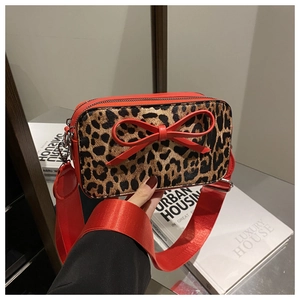 Detail of leopard print crossbody bag with a large red bow and matching wide strap