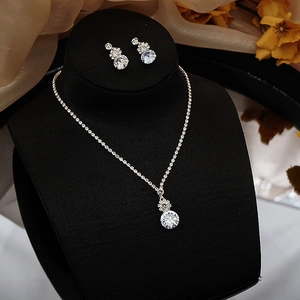 Close-up of sparkling zircon tassel necklace and earrings set on a black display stand