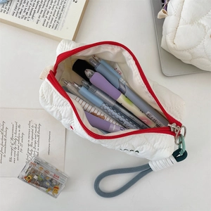 Spacious white quilted pencil case with red zipper trim and multiple pens stored inside