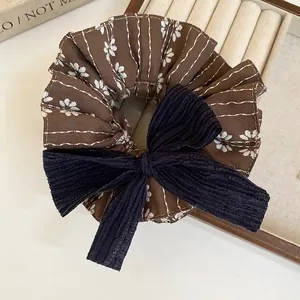 Vintage-Haargummi mit Blumenmuster und großer dunkelblauer Schleife auf einem Holztablett