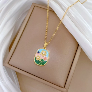 Macro view of gold stainless steel necklace with floral enamel oval pendant detailing