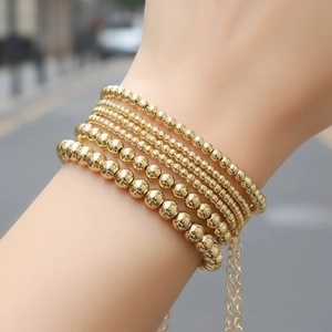 Minimalist gold beaded bracelet set with multiple layers of polished metallic beads