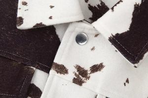 Close-up of cow print velvet collar detail and silver metal button on long sleeve jacket