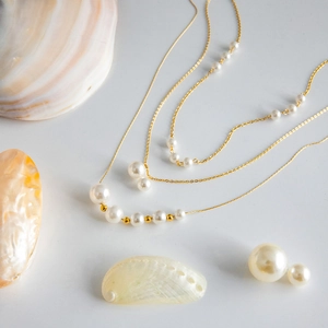 Detail of multi-layer 18k gold stainless steel necklace with graduated pearls and earrings