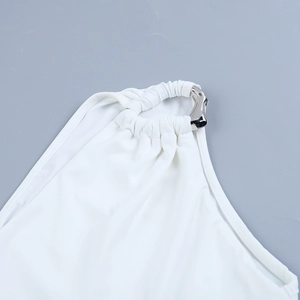 Close-up of white summer dress featuring silver metal ring and pleated fabric detail