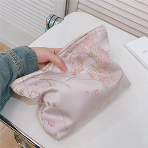 Vue détaillée d'une trousse à maquillage en satin rose avec motifs dorés jacquard