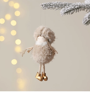Close-up of plush angel doll Christmas ornament hanging on a snowy pine branch