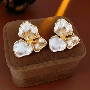 Macro shot of white floral earrings with golden edges and lustrous pearly petals