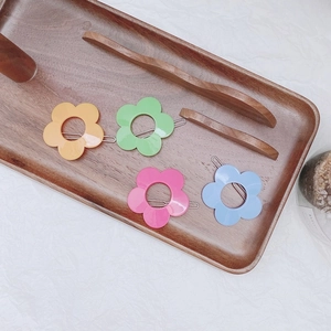 Set of 4 colorful flower hair clips in pink, blue, green and orange on wood tray