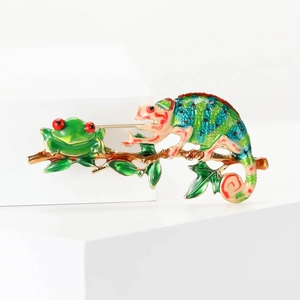 Detail view of colorful enamel chameleon and frog on a branch brooch with polished finish