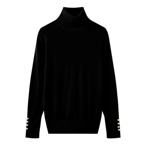 Detailed view of women's black turtleneck knit sweater with gold cuff buttons