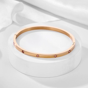 Detail of rose gold titanium bracelet with pink zircon stones and screw patterns