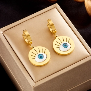 Close-up of golden evil eye teardrop earrings with blue and white enamel inlay