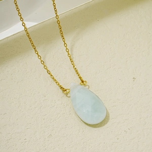 Détail macro du pendentif en pierre goutte bleu clair avec collier chaîne en or chic