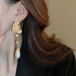 Detail of vintage gold flower drop earrings with white pearls on a model