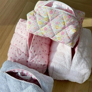 Close-up of stacked quilted cosmetic bags in floral, striped, and plush fabric styles