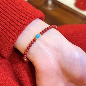 Detail eines roten Achat-Perlenarmbands mit türkisfarbenem Akzent am Handgelenk