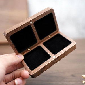 Handheld view of black walnut jewelry box with four compartments and black velvet lining