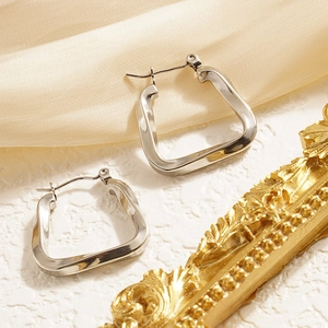 Silver geometric U-shaped twisted earrings on silk fabric with vintage gold frame accent