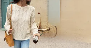 Close-up of beige cable knit sweater featuring round neck design and textured patterns