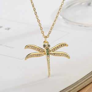 Detail view of 18K gold plated dragonfly pendant necklace with green and white crystals